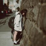 石の壁に向かってうな垂れる女子高生