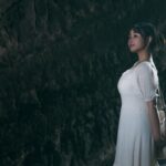 トンネルのなかで出口を見つめる白いワンピース姿の若い女性